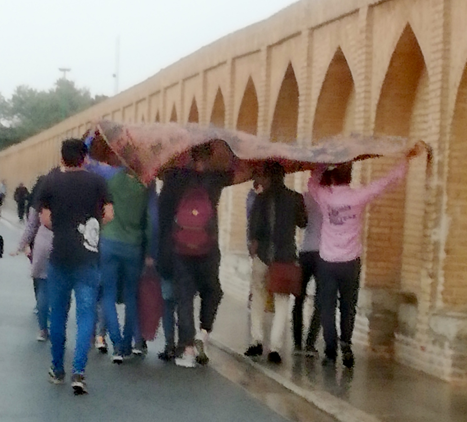 men carrying a carpet as an umbrella in Isfahan