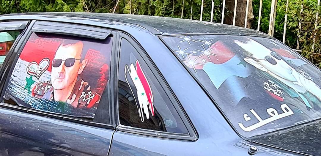 A car covered in images of President Assad in Syria