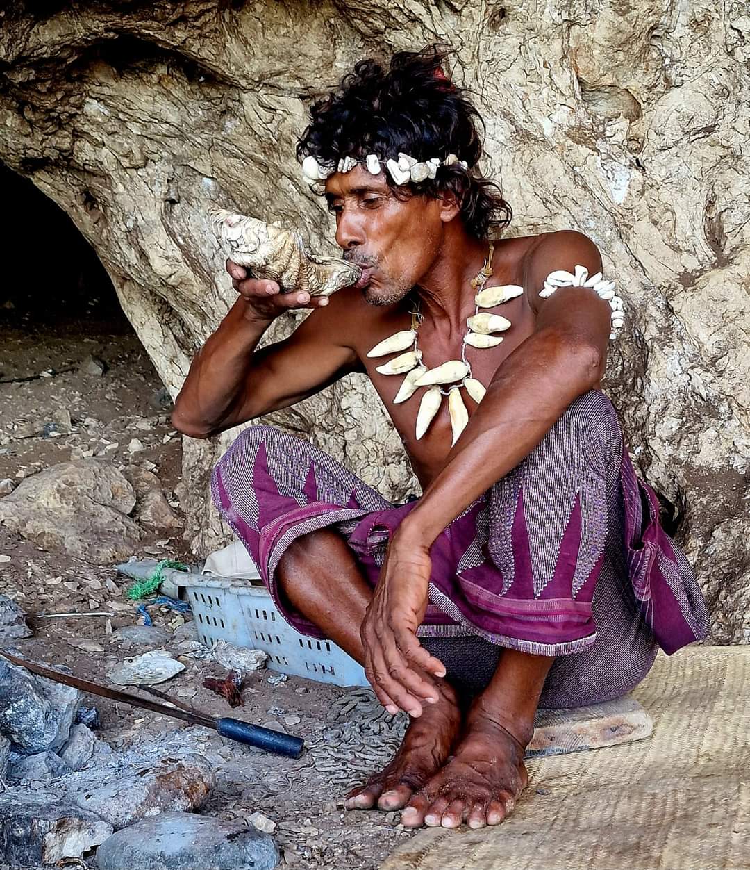 The caveman uses a seashell as a cup to drink his tea